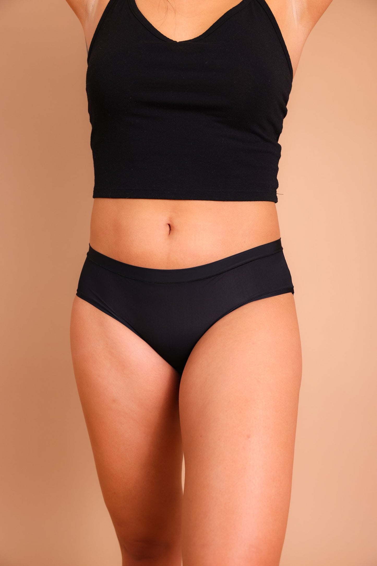 A person models a black crop top and The Pocket Panty by Sonia's Vokalized Kreations, set against a beige background.