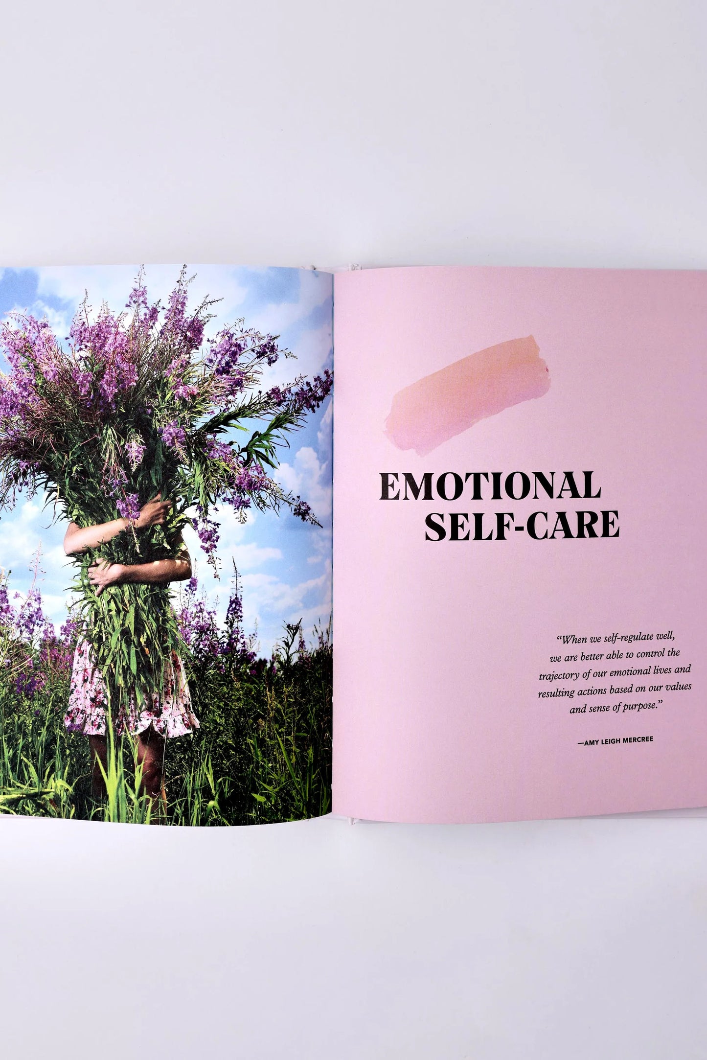 An open book reveals a captivating photo of someone holding large purple flowers on the left, while the right pink page reads "Self Less Care" by Sonia's Vokalized Kreations, offering suggestions to rejuvenate your body and spirit.