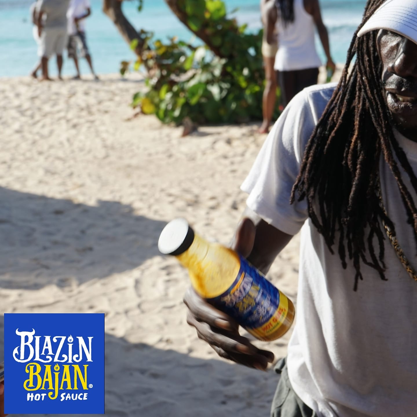 On a sunlit beach, a person relaxes while holding a bottle of Seasoned by Sonia's Vokalized Kreations. The logo of the brand enhances their seaside adventure with a spicy flair.