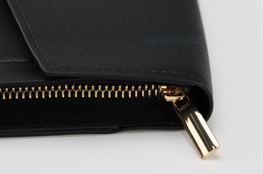 Close-up of the Harlem Clutch from Sonia's Vokalized Kreations' Harlem & Brooklyn Bundle, showcasing a black leather design with a visible gold zipper and pull tab, partially open.