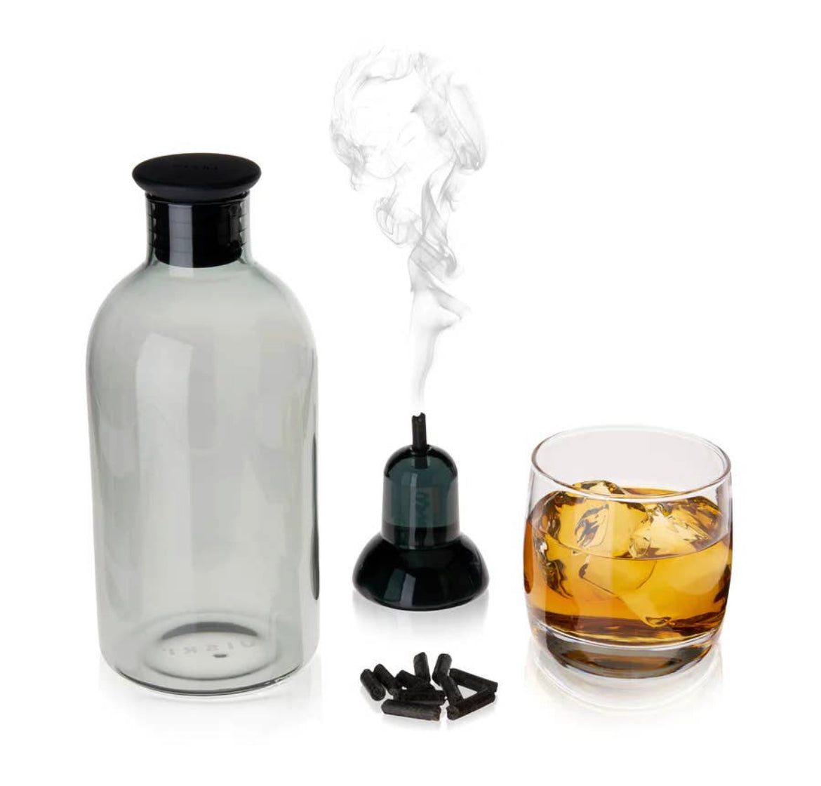 The Alchemi Smoked Cocktail Kit by sonia's-vokalized-kreations features a smoke infuser, glass container, and whiskey-soaked oak garnished glass of amber liquid with ice on a white surface. Black smoking chips lie next to the infuser, offering a compact flavor enhancement solution.