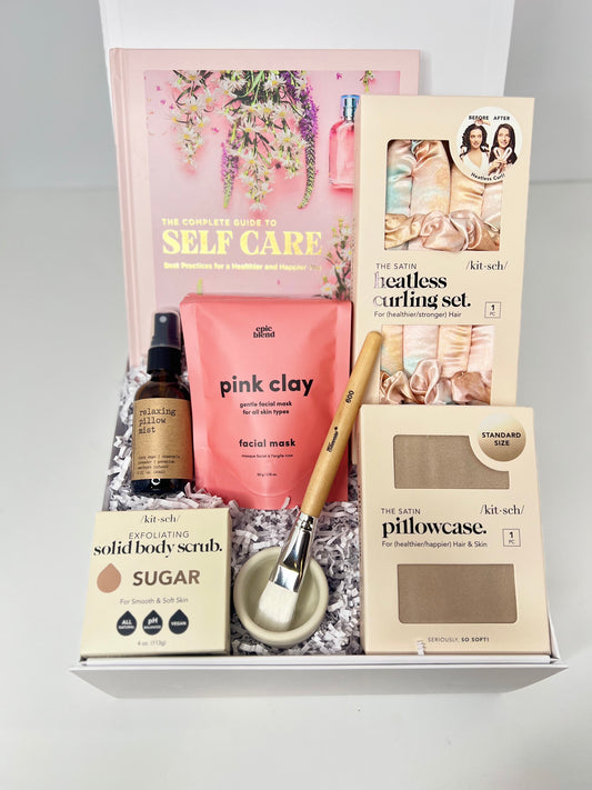 Treat yourself to Sonia's Vokalized Kreations' "Self Less Care" box, featuring a self-care guide, pink clay mask, heatless curlers, pillowcase, solid scrub, facial brush, and hair serum for the ultimate pampering experience.