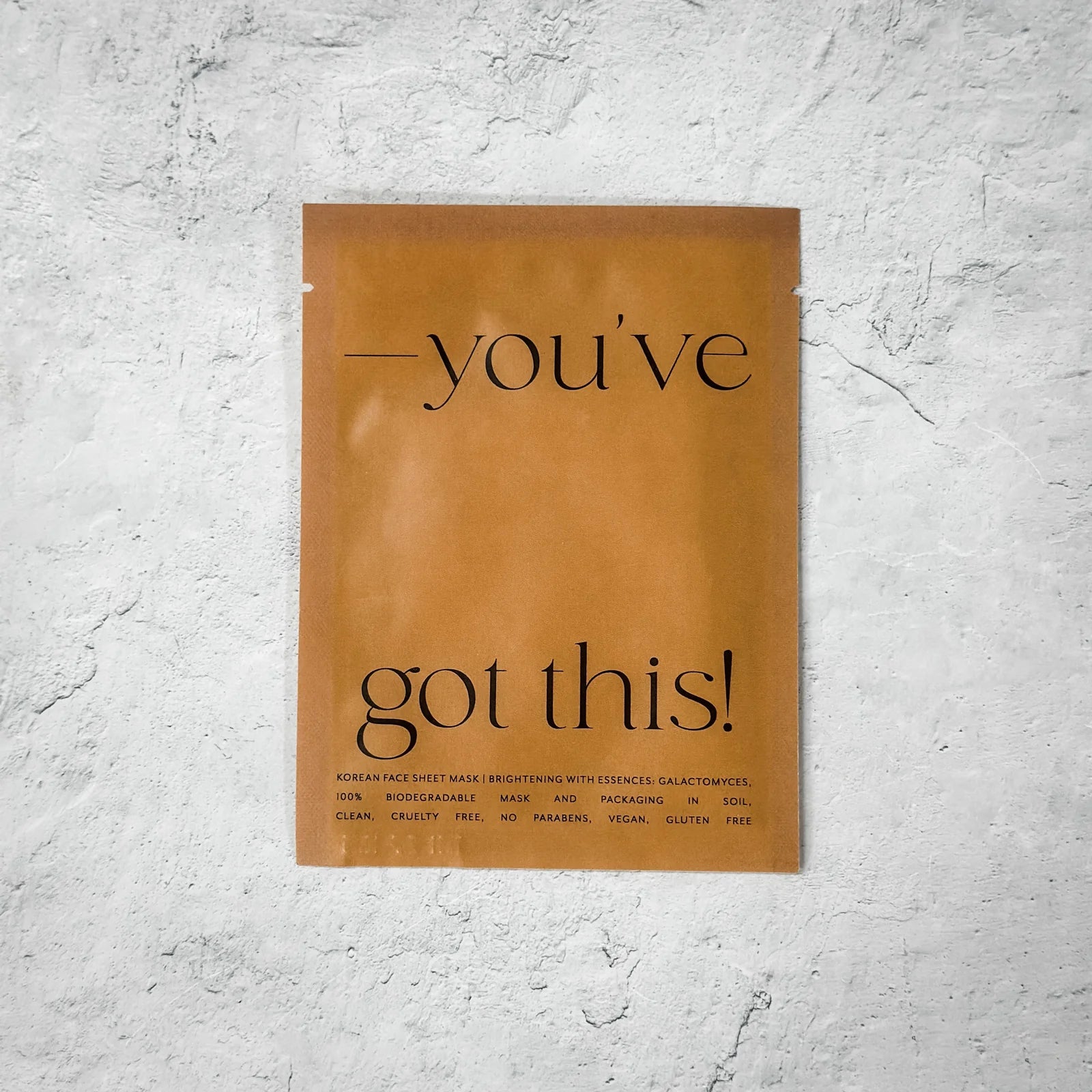 The brown sheet mask packaging features the text "--you’ve got this!" on a textured gray background. It's biodegradable, cruelty-free, vegan, and gluten-free—ideal for rejuvenation before reaching for your Diaper Clutch or saying, "Mommy Let's Cuddle" from Sonia's Vokalized Kreations.