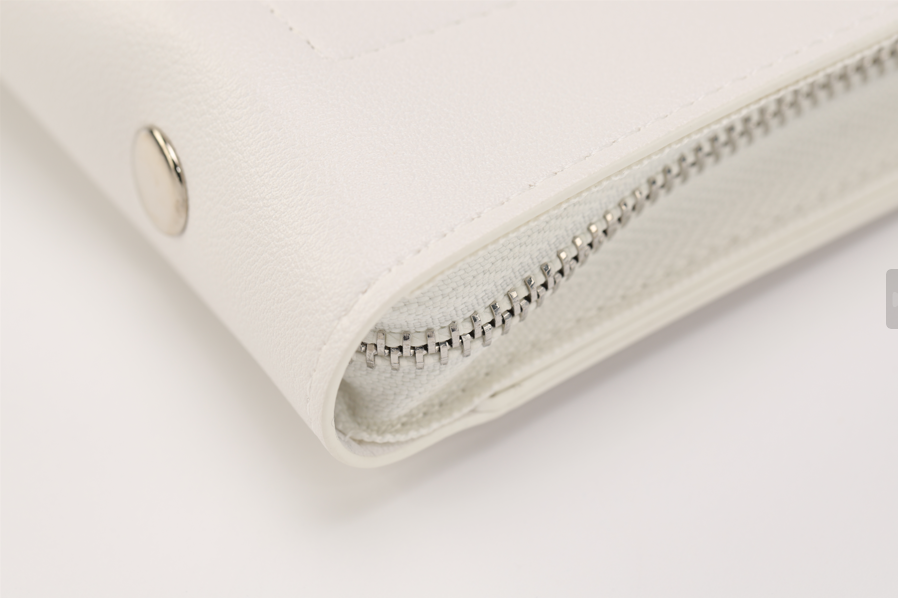 Close-up of Paloma bag by Sonia's Vokalized Kreations, featuring a bold statement with a visible silver zipper and metal button, set against a white background.