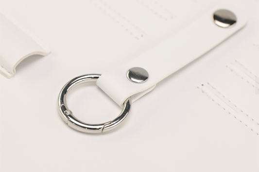 A close-up of Paloma by Sonia's Vokalized Kreations reveals a bold white leather strap accented with a metal ring and two metal studs, perfect for the fearless woman.