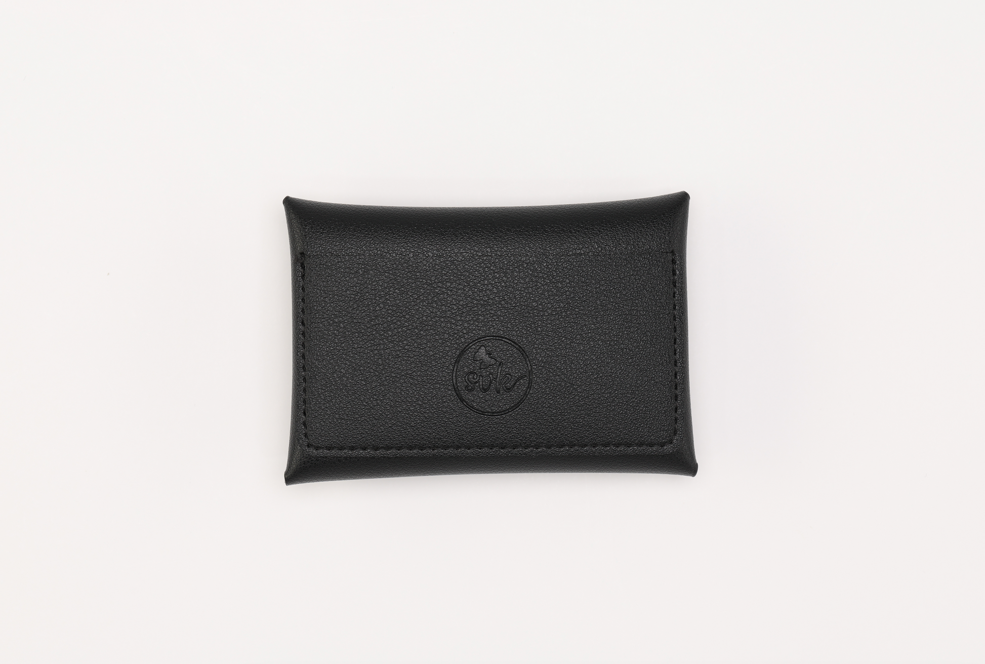 Sonia's Vokalized Kreations' Harlem & Brooklyn Bundle features a classic black leather pouch with an embossed circular logo on a white background, echoing the timeless elegance of the Brooklyn Wallet. Perfect for discerning collectors seeking sleek sophistication.