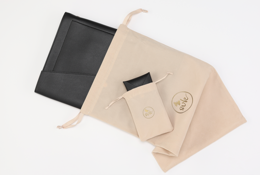 The Harlem & Brooklyn Bundle by Sonia's Vokalized Kreations, featuring the black document holder and Harlem Clutch in beige drawstring bags on a white background, highlights the allure of classic black accessories.