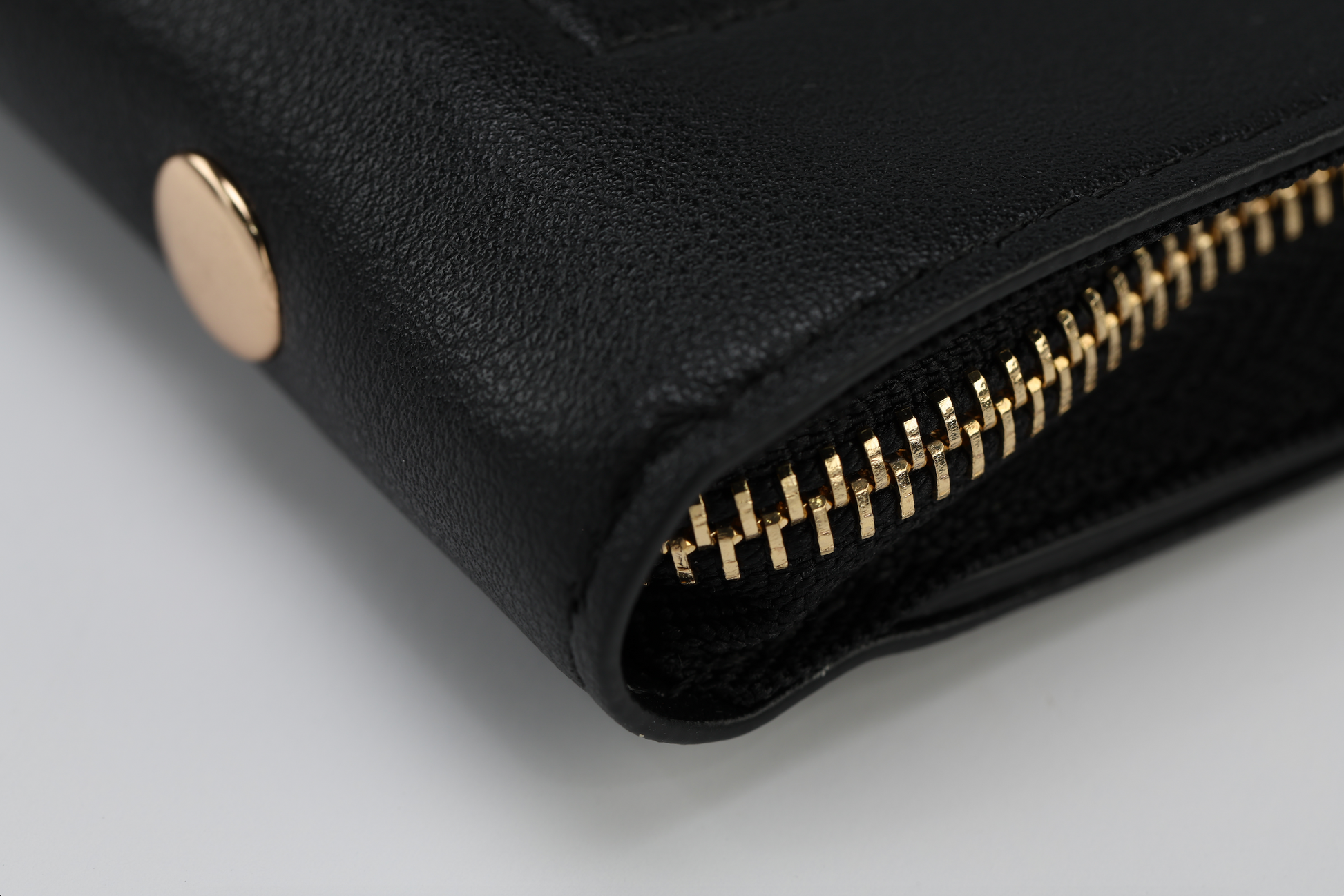 Showcase the elegance of classic black accessories with a close-up of the Harlem & Brooklyn Bundle by Sonia's Vokalized Kreations. Crafted from sleek black leather, it features a gold zipper and button against a white background for stunning contrast.