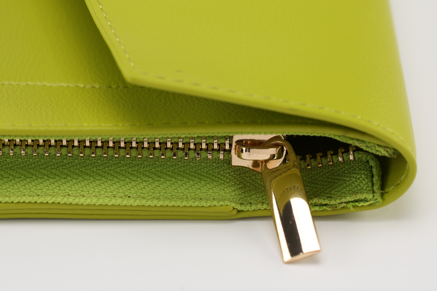 Close-up of a lime green leather wallet by Sonia's Vokalized Kreations, reminiscent of the bold Pompei style. It features a gold zipper partially open, revealing green fabric lining.