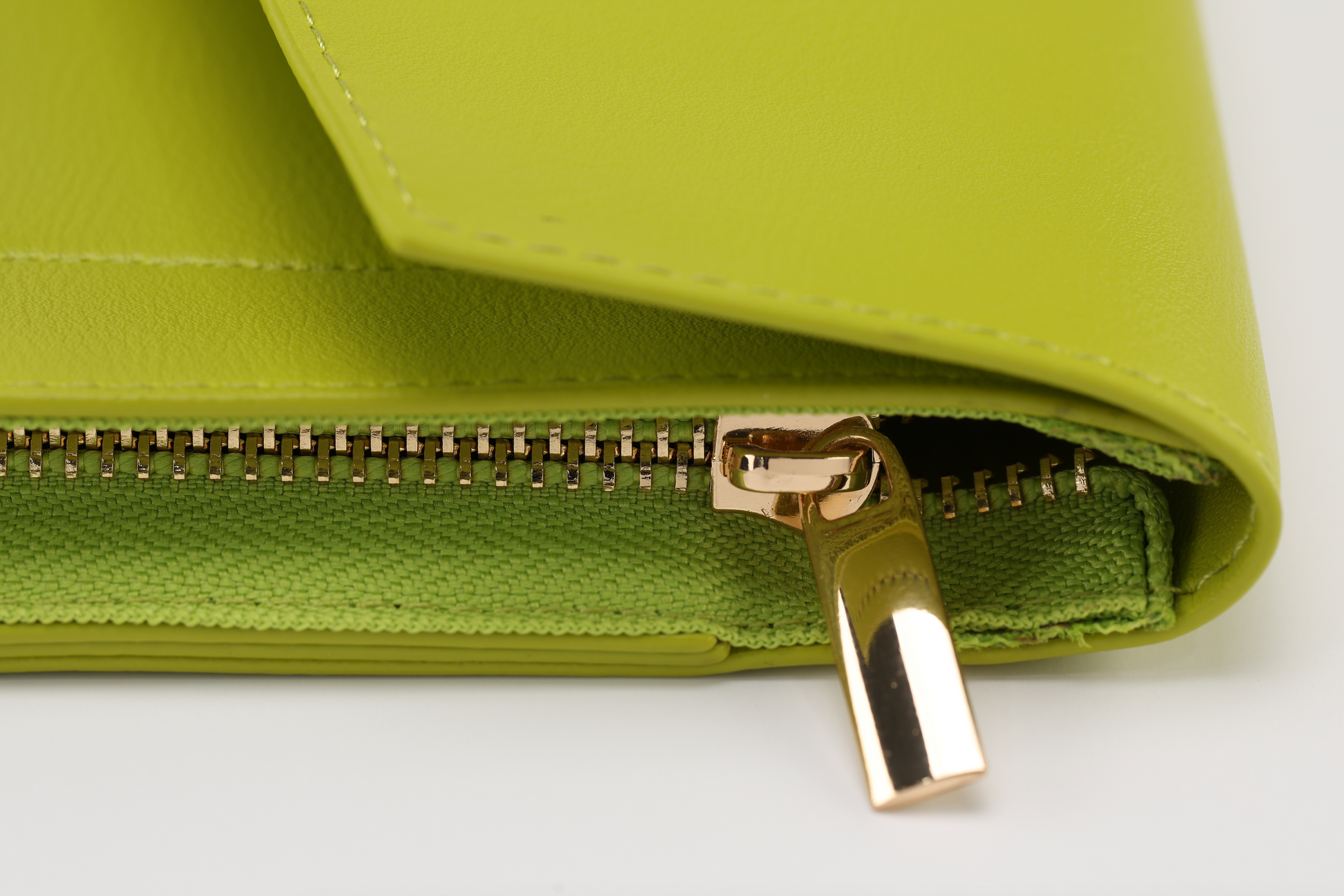 Close-up of a lime green leather wallet by Sonia's Vokalized Kreations, reminiscent of the bold Pompei style. It features a gold zipper partially open, revealing green fabric lining.