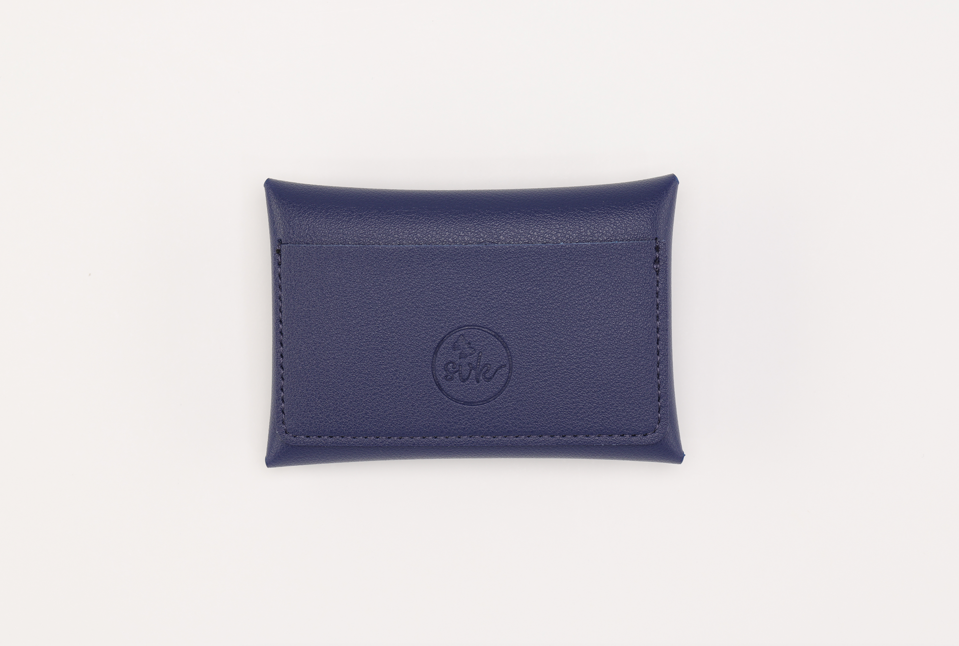 The Brooklyn Wallet 2.0 by Sonia's Vokalized Kreations is a compact blue leather cardholder featuring a rectangular shape, stitched edges, and a central circular embossed logo. It exudes sleek elegance against a simple white background.
