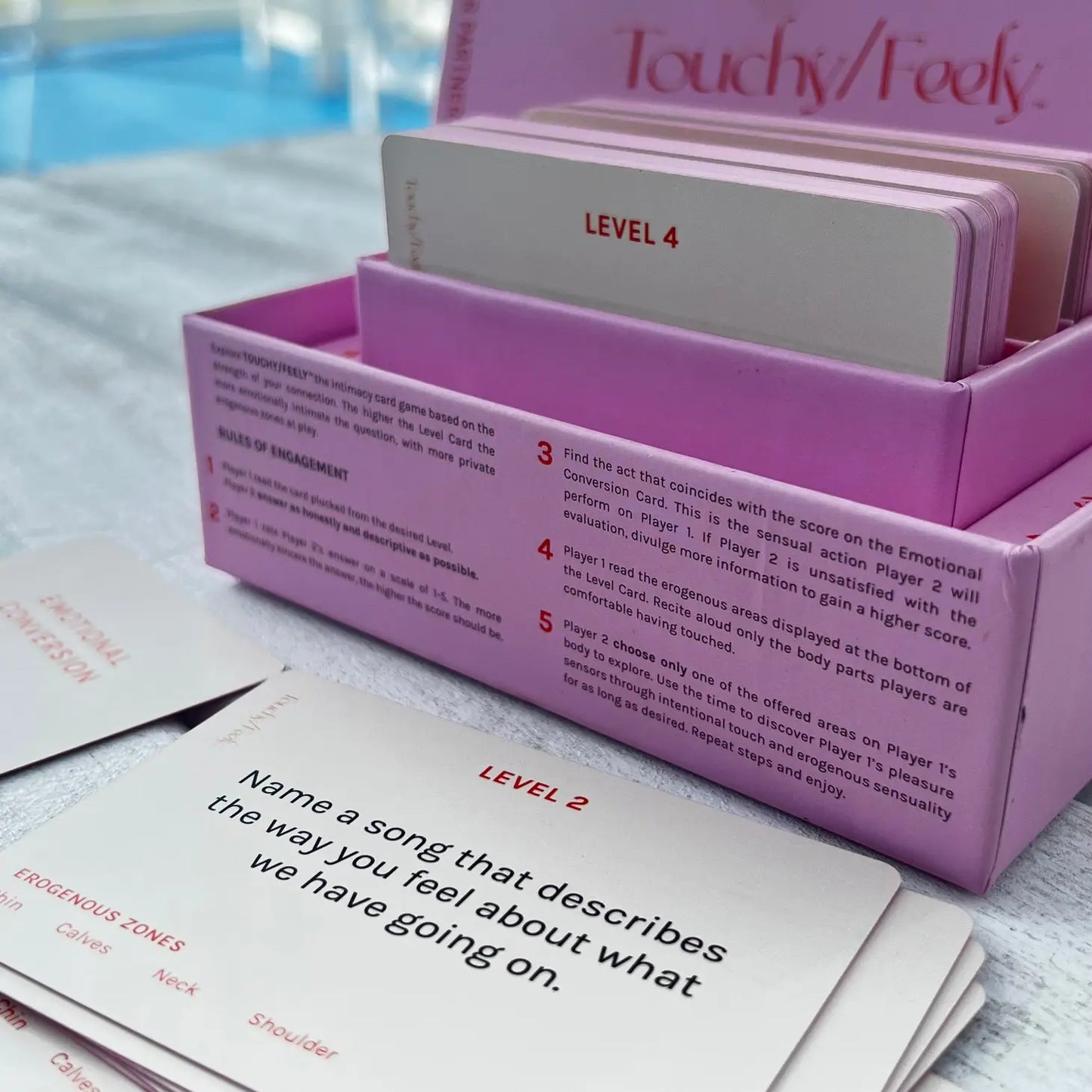 The Touchy/Feely™ Intimacy Card Game by Sonia's Vokalized Kreations has players explore their emotions through levels and prompts like "Name a song that describes the way you feel about what we have going on," with cards beautifully spread out on display.