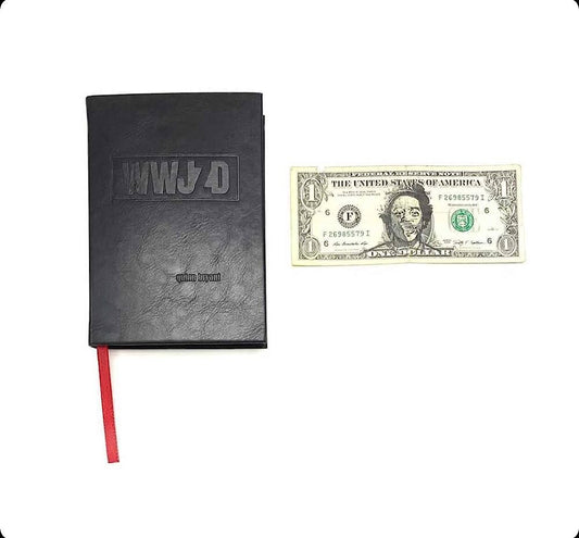 Black notebook with "WWJD" on the cover next to a U.S. one-dollar bill.