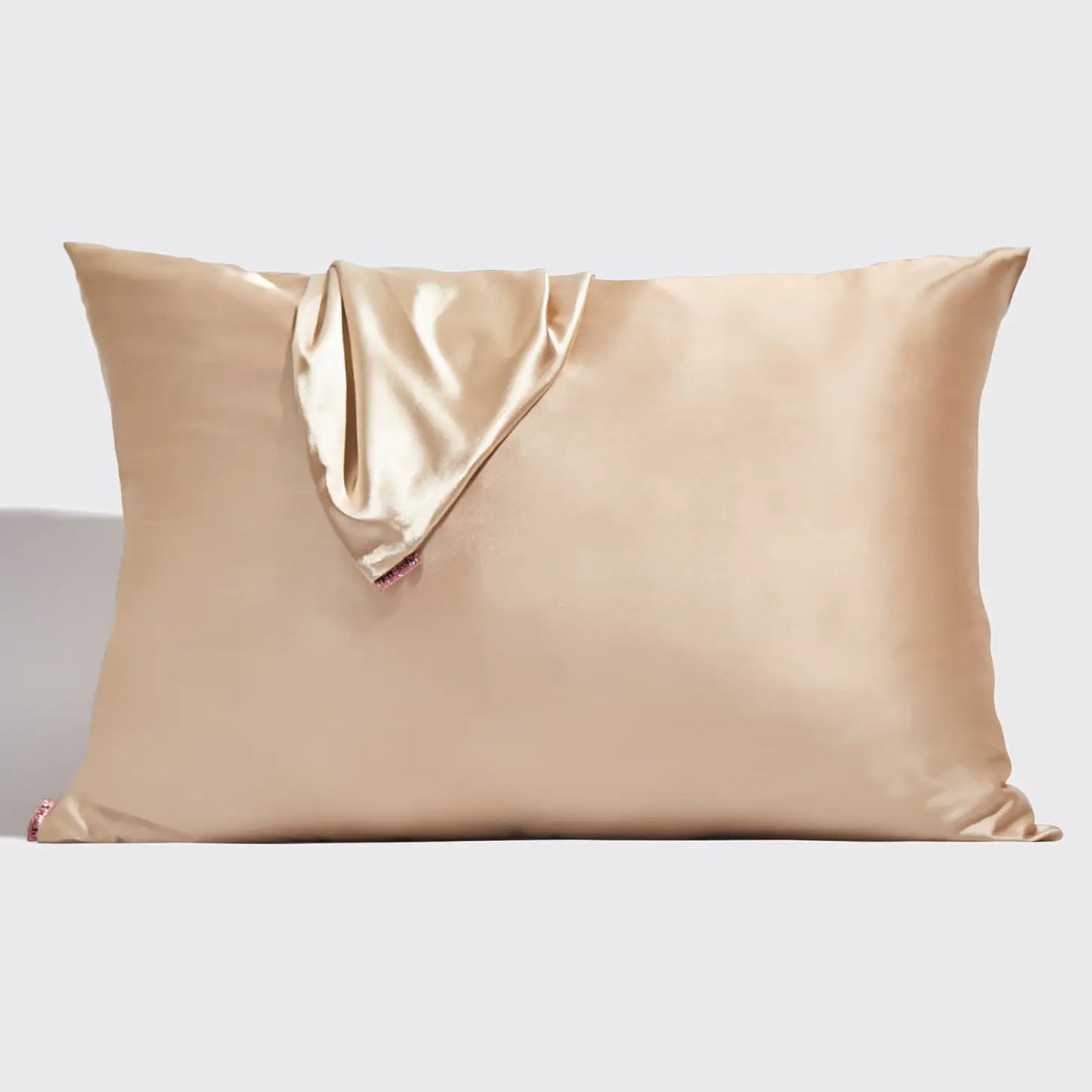 Sonia's Vokalized Kreations' Self Less Care features a beige satin pillowcase with a matching satin square draped over the top left corner, offering serene luxury and inviting rejuvenation for body and mind against a plain backdrop.