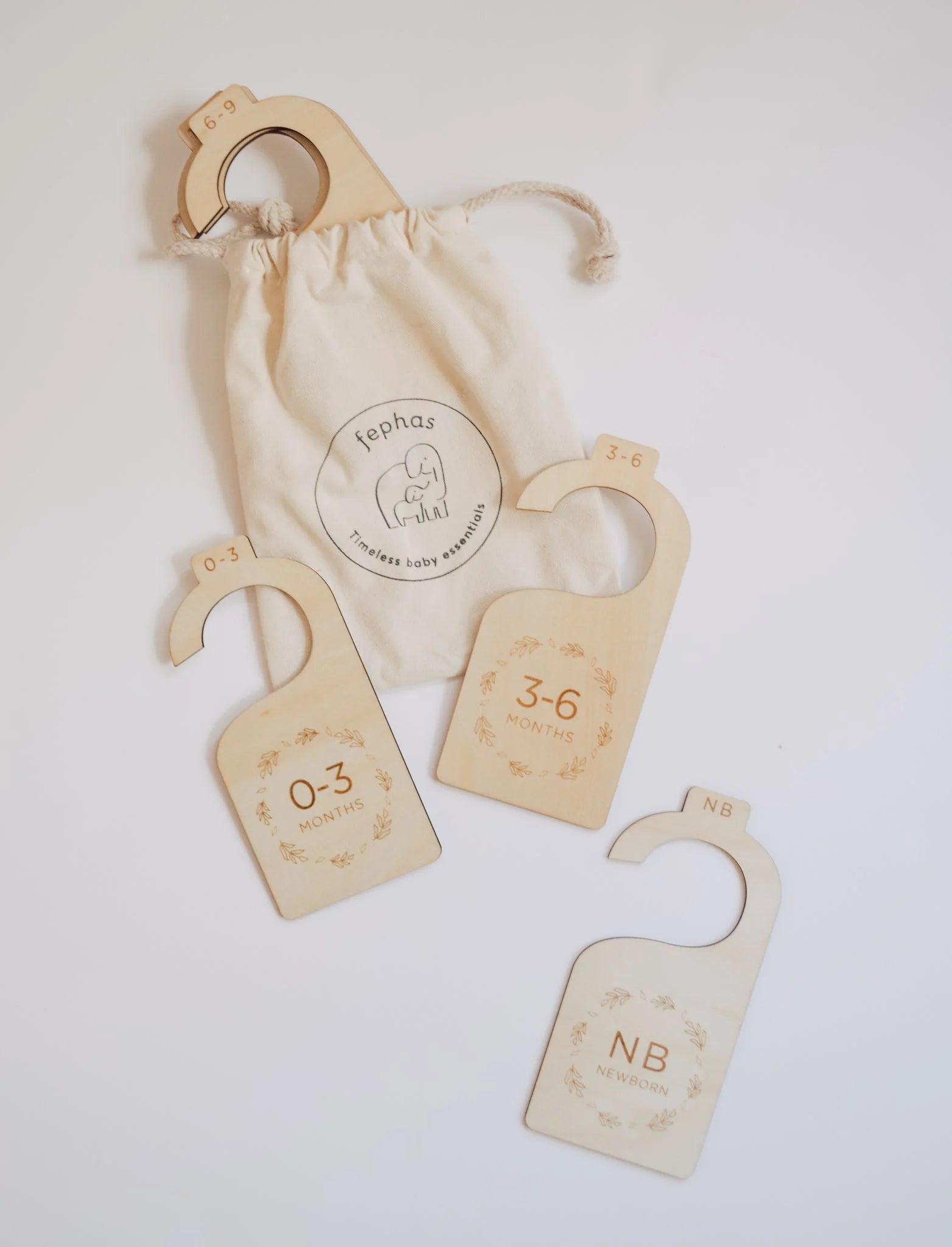 The New Baby Gift Box for Mom & Baby by Sonia's Vokalized Kreations includes three wooden closet dividers (“NB NEWBORN,” “0-3 MONTHS,” “3-6 MONTHS”) and a beige Fephas drawstring bag—perfect for organizing your baby's wardrobe.
