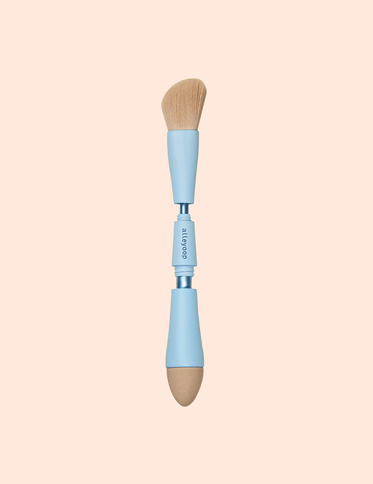 Sonia's Vokalized Kreations' 4 in 1 Makeup Brush is a travel-friendly tool featuring a fluffy angled brush on one end and a rounded sponge applicator on the other, both with light blue handles, perfect for effortless beauty on the go.