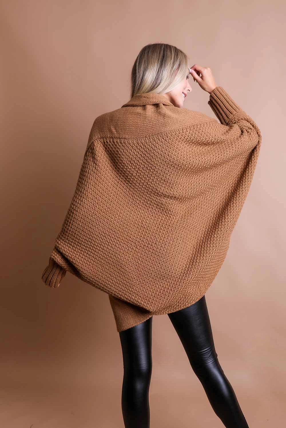 Person wearing a Bat Sleeve Knit Cardigan from Sonia's Vokalized Kreations and black leather pants, standing against a beige backdrop.