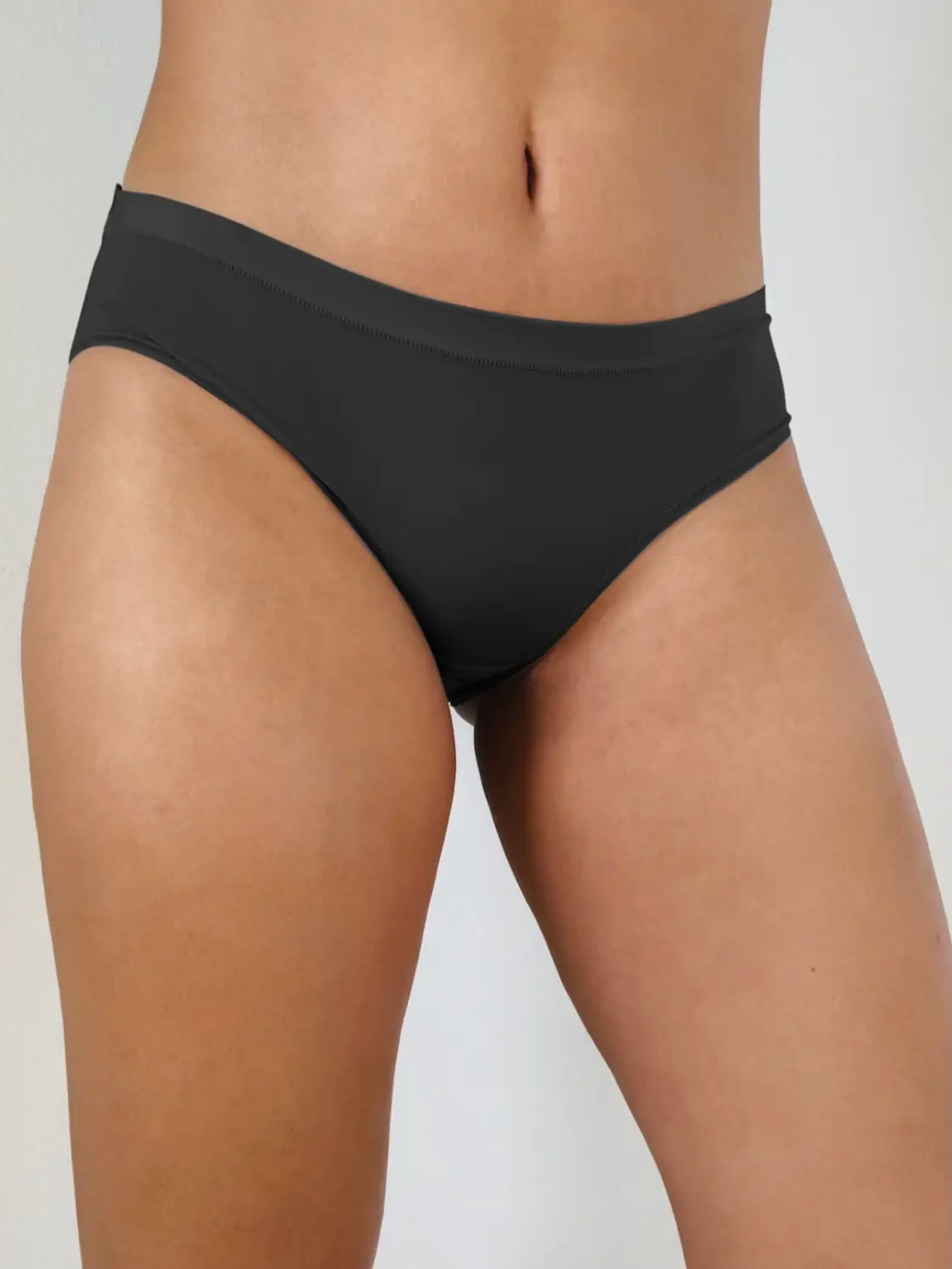 A person is shown wearing The Pocket Panty, dark gray biodegradable bikini bottoms from Sonia's Vokalized Kreations, set against a light background.