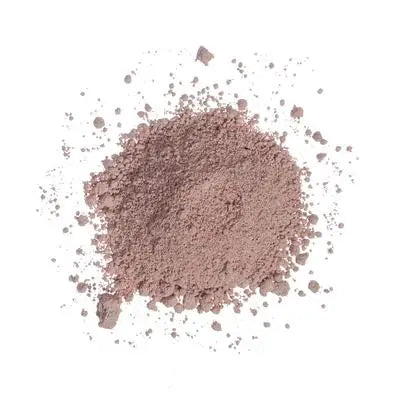 A pile of light brown powder, similar to French pink clay, is scattered on a white background. This resembles the texture of Sonia's Vokalized Kreations' Pink Clay Facial Mask.