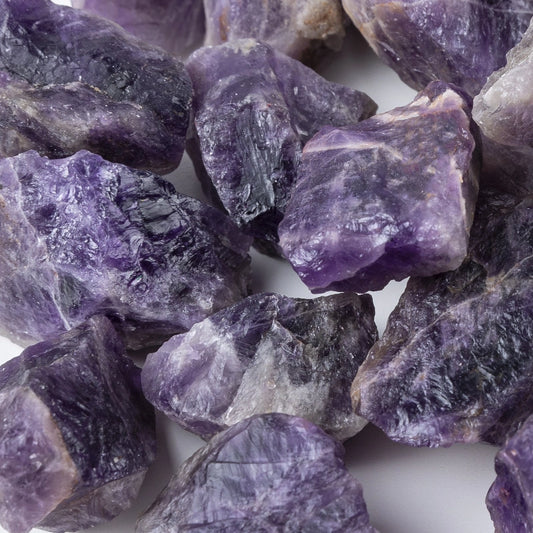 Sonia's Vokalized Kreations' Himalayan Salt Gemstone Diffuser features rough amethyst stones with deep purple and white hues, scattered beautifully on a pristine white base.
