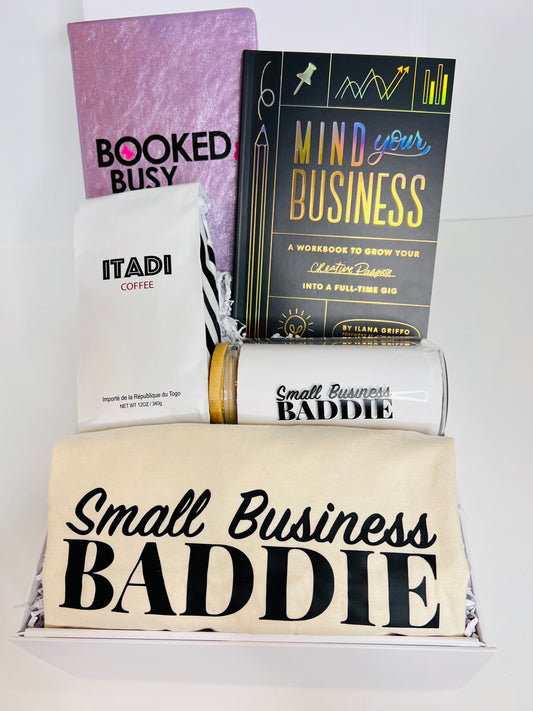 The Boss Chic Essentials gift box by sonia's-vokalized-kreations is perfect for the entrepreneurial woman, featuring a pink notebook, "Mind Your Business" workbook, coffee bag, candle, tumbler, and a tote with "Small Business Baddie" text.