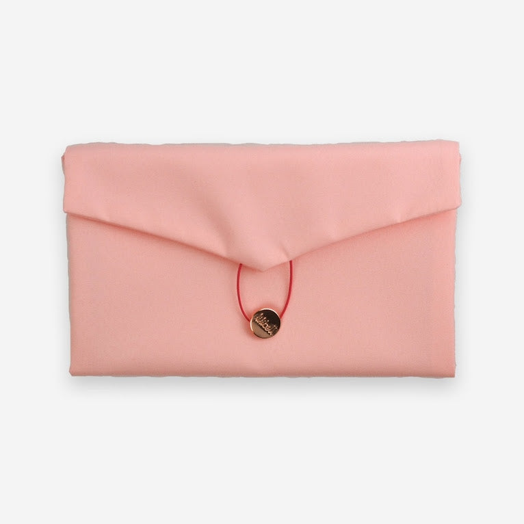 The Daily Daisy Swaddle Bag by Sonia's Vokalized Kreations is a versatile pink fabric clutch with a triangular flap, red string closure, and a round golden button—perfect for any occasion.
