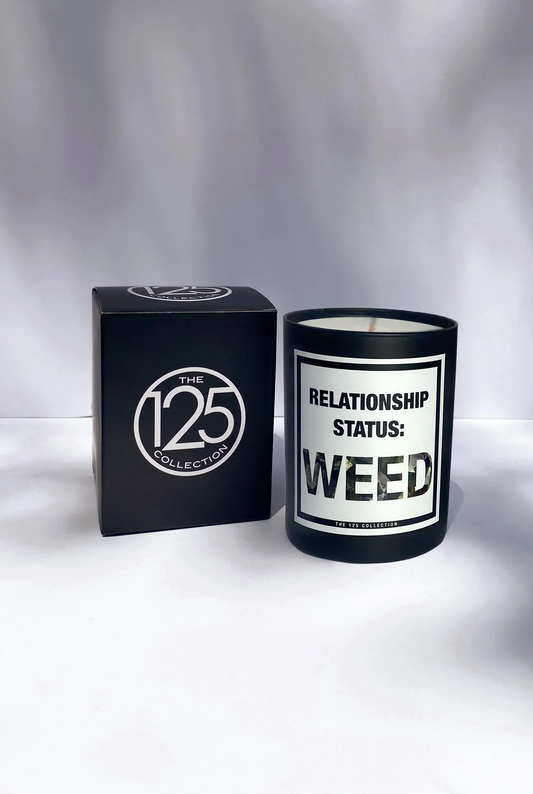 A black "Relationship Status Weed" candle made from vegan soy wax sits beside a sleek black box with "Sonia's Vokalized Kreations" logo. Infused with premium fragrance oil, this candle delivers an aromatic experience that enhances any space.