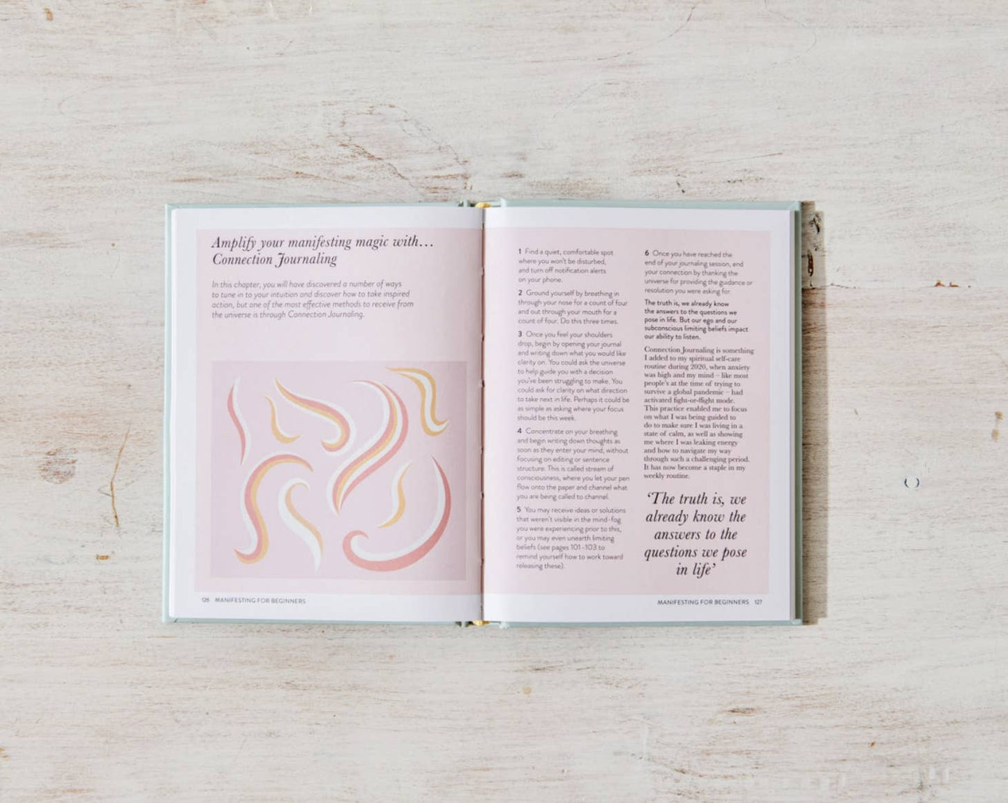 A copy of "Manifesting For Beginners" by Victoria Jackson from sonia's-vokalized-kreations lies open on a light surface, its pages filled with insights and abstract pastel illustrations that promote positive energy and personal growth through conscious journaling and thoughtful reflection.