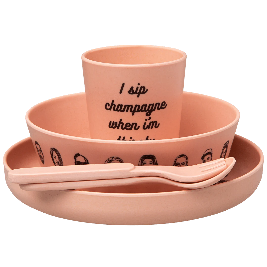 Sonia's-vokalized-kreations' Baby Bamboo Dinnerware Set includes a hip-hop inspired pink cup, bowl, plate, fork, and spoon with illustrated faces. Made from eco-friendly bamboo, the cup features the phrase "I sip champagne when I'm thirsty.