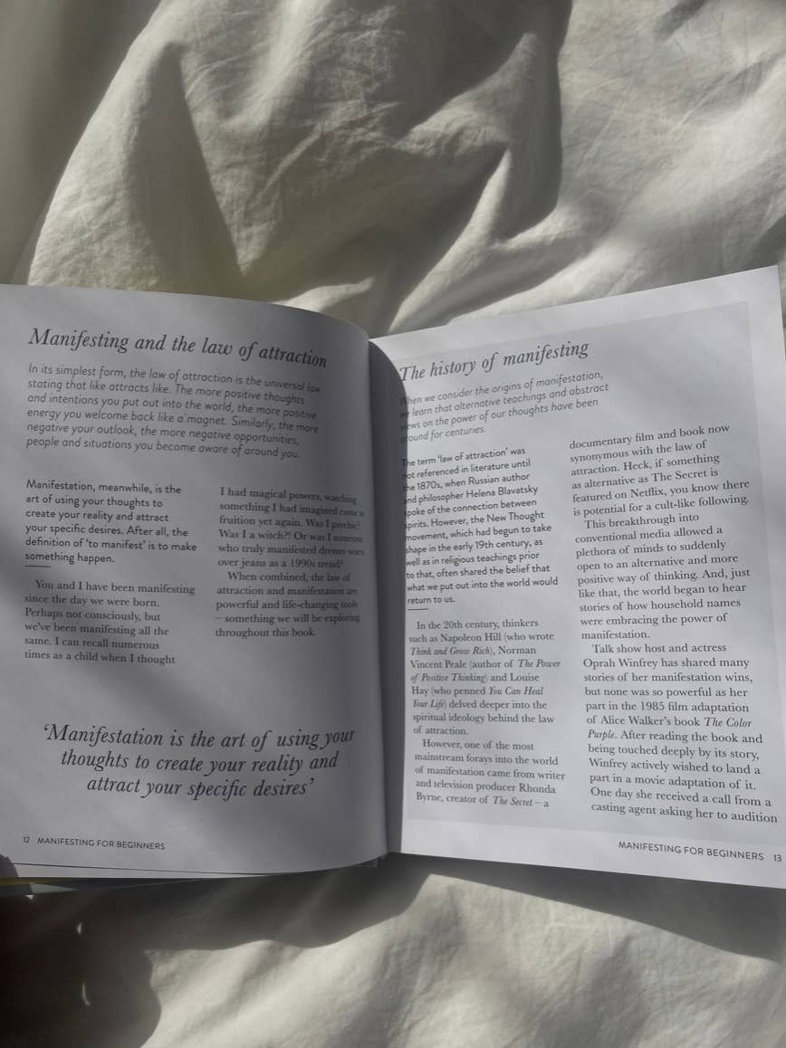 Manifesting For Beginners by Victoria Jackson from sonia's-vokalized-kreations is open on the sunlit bed. Its pages explore manifesting and positive energy. Though legible, text details blur slightly as they discuss mindset shifts and the history of attraction's influence.