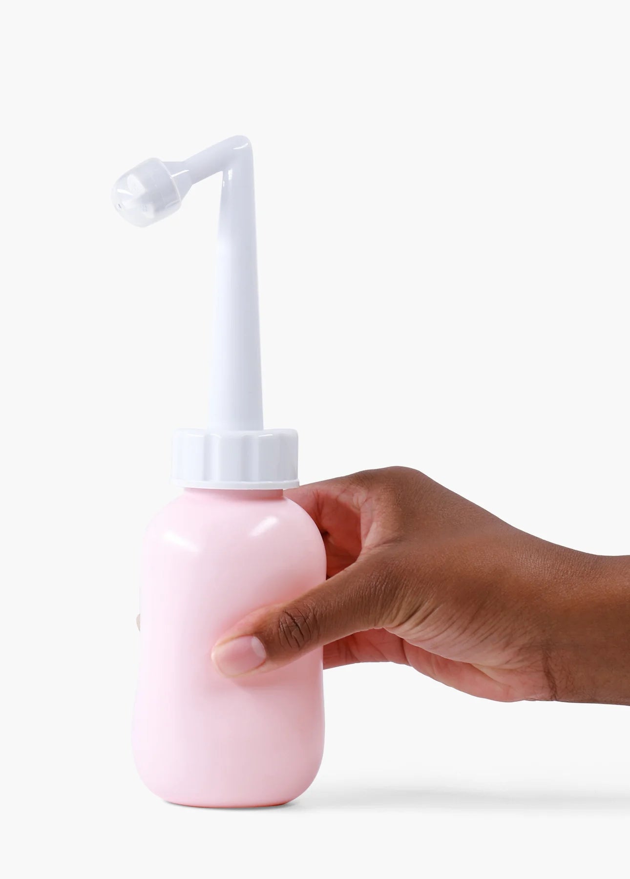 A hand holds a Peri Bottle by sonia's-vokalized-kreations featuring a pink plastic design and white angled nozzle against a white backdrop, highlighting this essential postpartum tool for gentle perineum care.