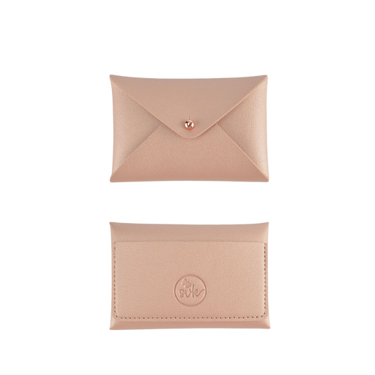 Two beige leather envelope-style pouches from "sonia's-vokalized-kreations" Brooklyn Collection lie on a textured dark surface. The top wallet closes with a button, and the bottom one displays a circular logo—ideal for women on the go.