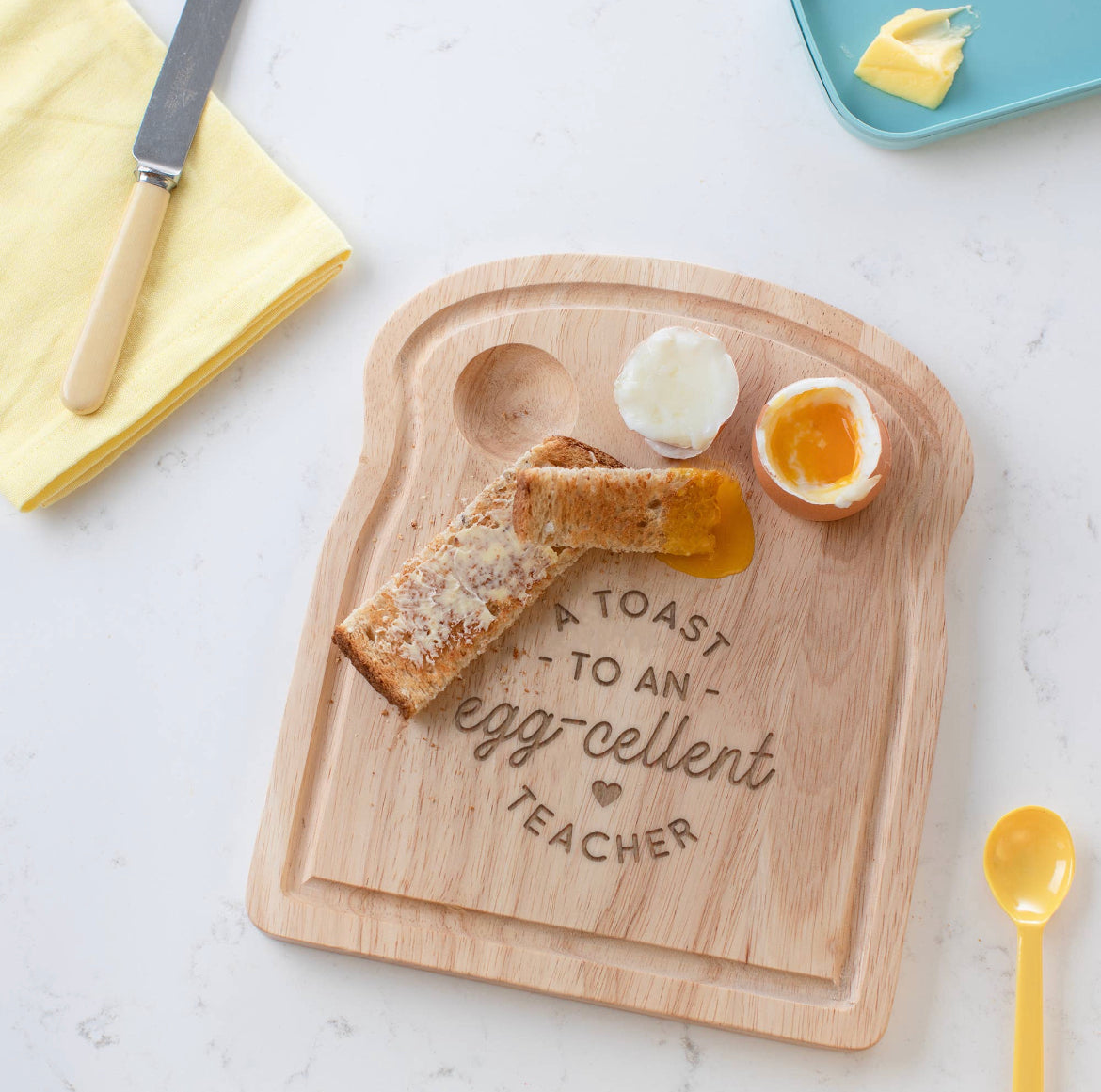The Egg Breakfast Board by sonia's-vokalized-kreations, toast-shaped and engraved with "A toast to an egg-cellent teacher," perfectly holds toast and two soft-boiled eggs. Includes a knife, butter, and napkin—making it a delightful gift for teachers.