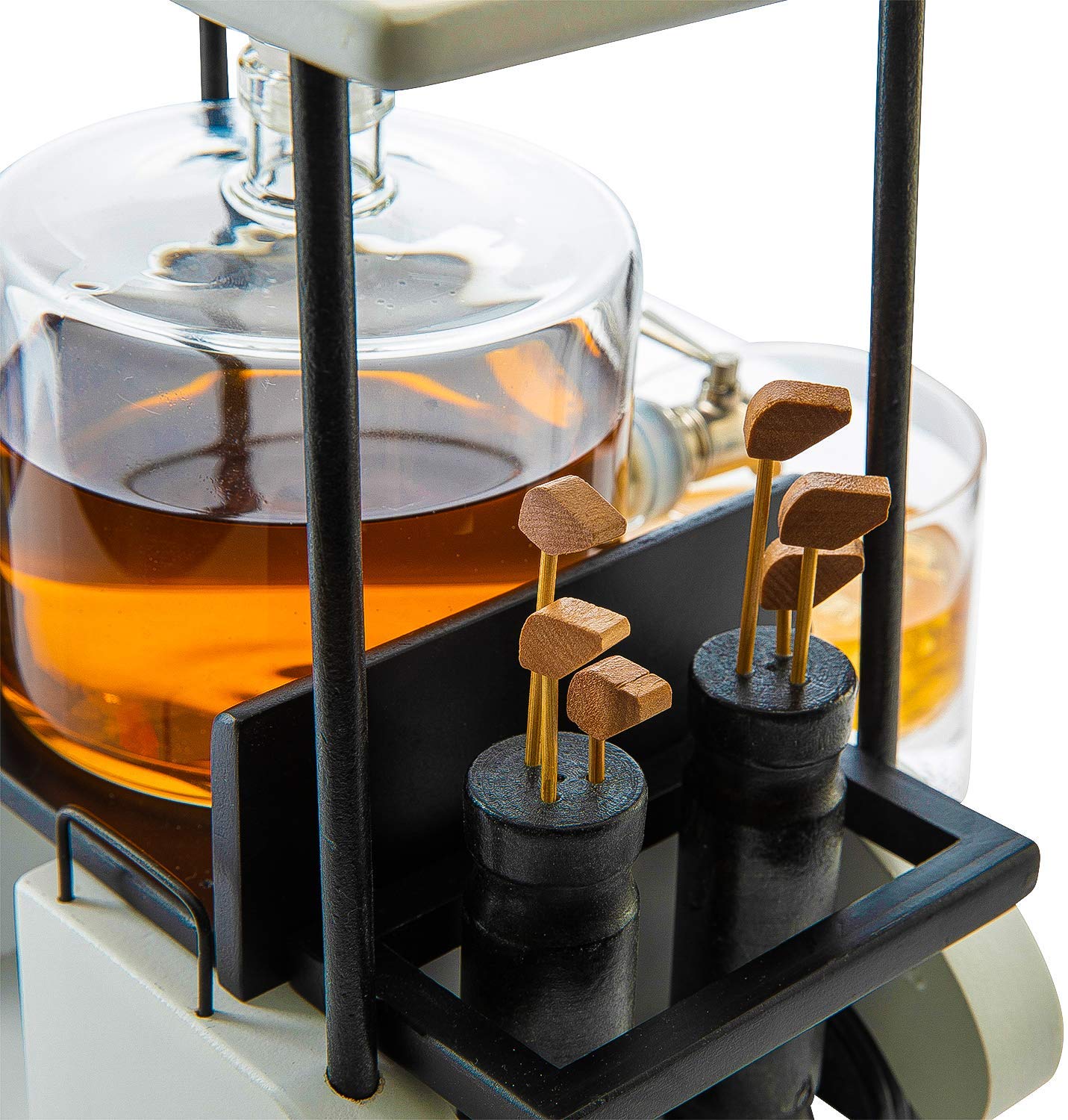 A close-up of Sonia's Vokalized Kreations' Golf Cart Decanter, featuring brown liquid in lead-free glasses with wooden stirrers on black racks. Its golf ball design blends mechanical and scientific elements, making it a true conversation piece.