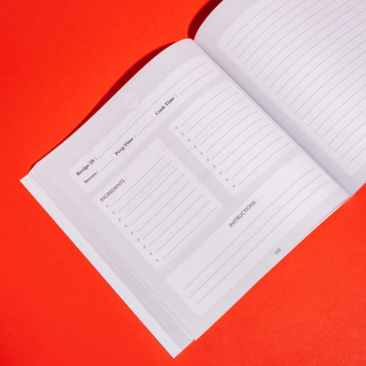 The "Mom, I Want To Learn Your Recipes" journal by Sonia's Vokalized Kreations is open on a red surface, with sections for recipe name, prep time, cook time, servings, ingredients, and instructions to preserve cherished recipes.
