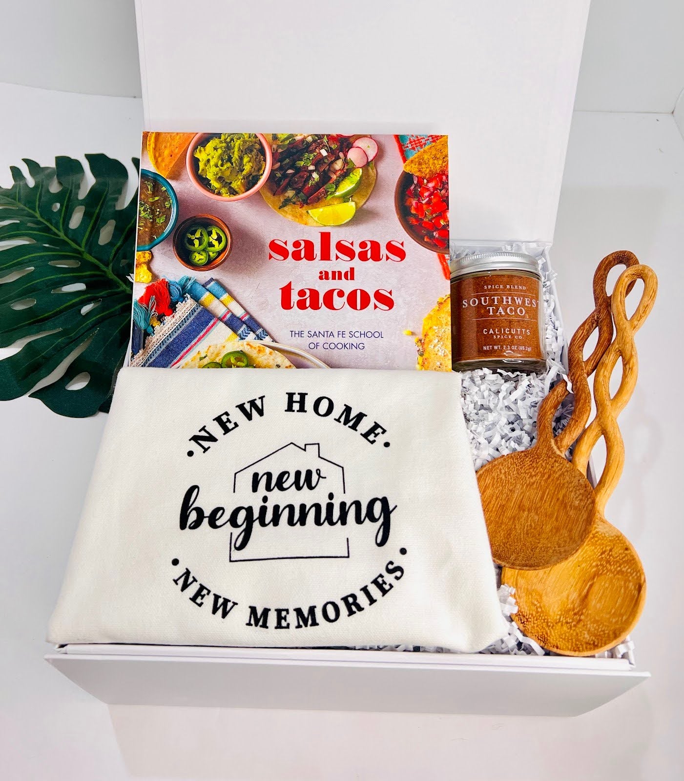 The Taco ‘Bout a New Beginning” Unique Housewarming Box by Sonia's Vokalized Kreations includes a Salsas & Tacos cookbook, “New Home, New Beginning, New Memories” pouch, Southwestern Taco Spice Blend, and two wooden utensils.
