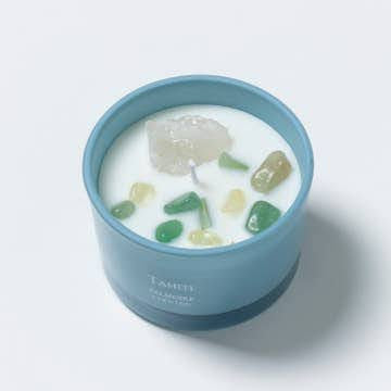 The Boho Self-Care Home Gift Box by Sonia's Vokalized Kreations features a blue soy wax candle with white wax, a central wick, and assorted green and yellow stones—ideal as a unique gift or for everyday relaxation.