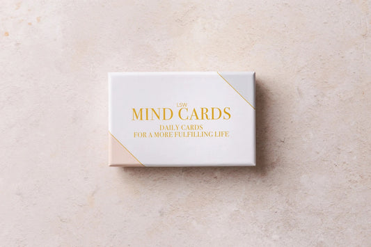 A box of "Mind Cards: Daily Cards" by sonia's-vokalized-kreations rests on a light textured surface, providing a daily boost to mental health and guiding you toward positive habits.